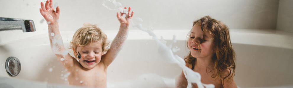 Twp young children splashing around in a bathtub